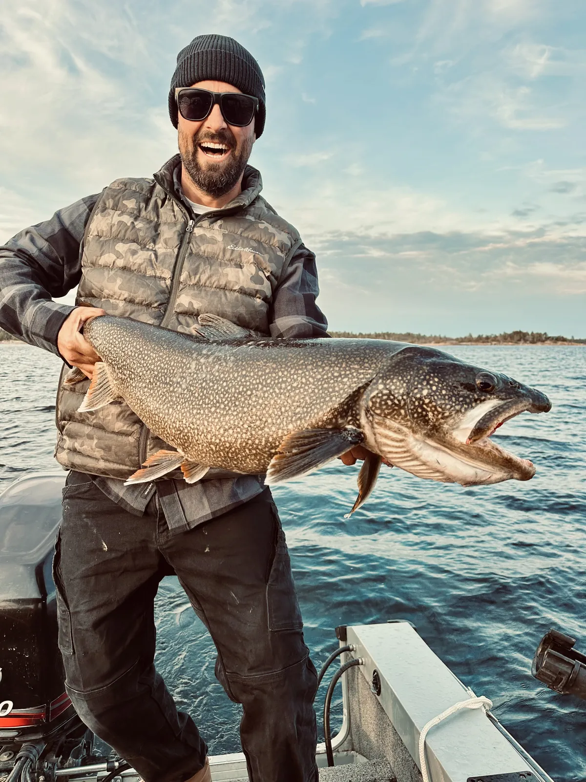 Dave Trerice holding a lake trout on the back of a boat