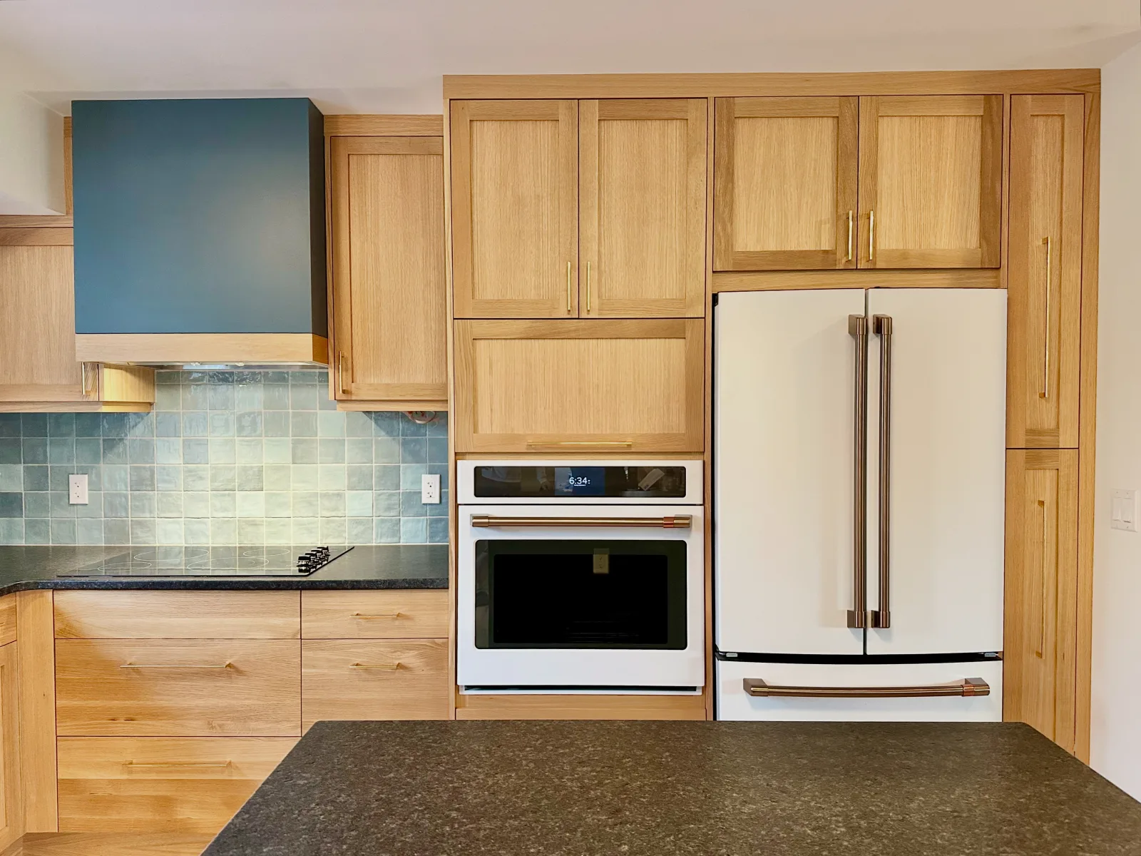 Hickory kitchen with a green range hood, white wall oven and a white fridge