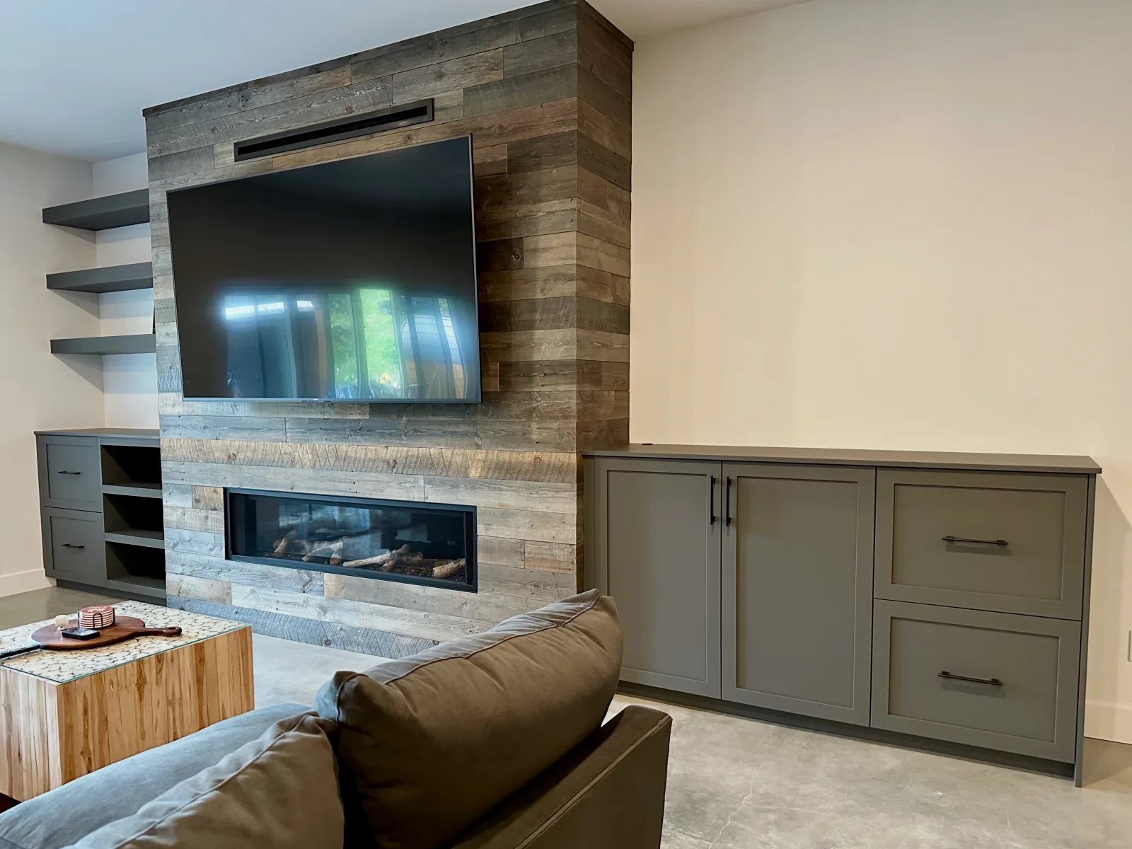 Media wall with a reclaimed wood surround, linear fireplace and grey cabinetry