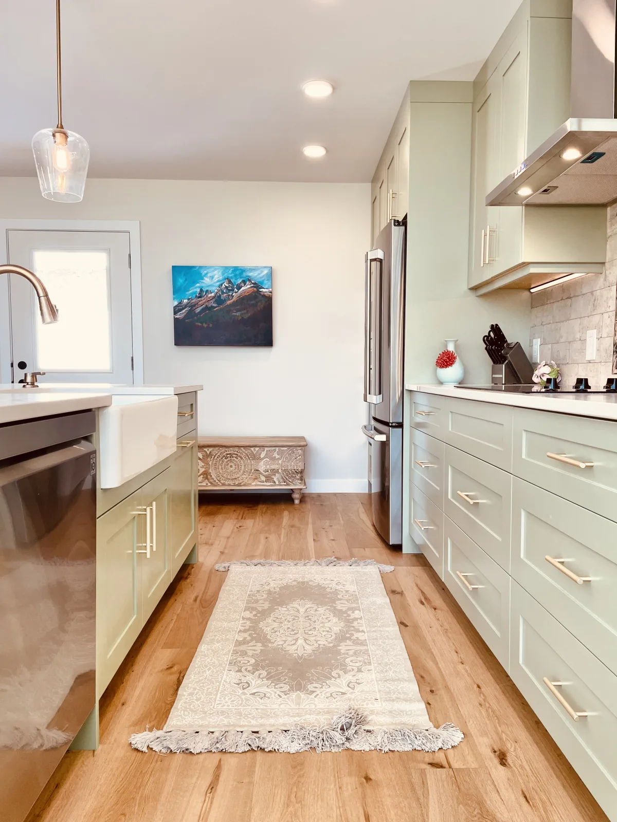 Sage green galley run with an apron sink and a panelled dishwasher