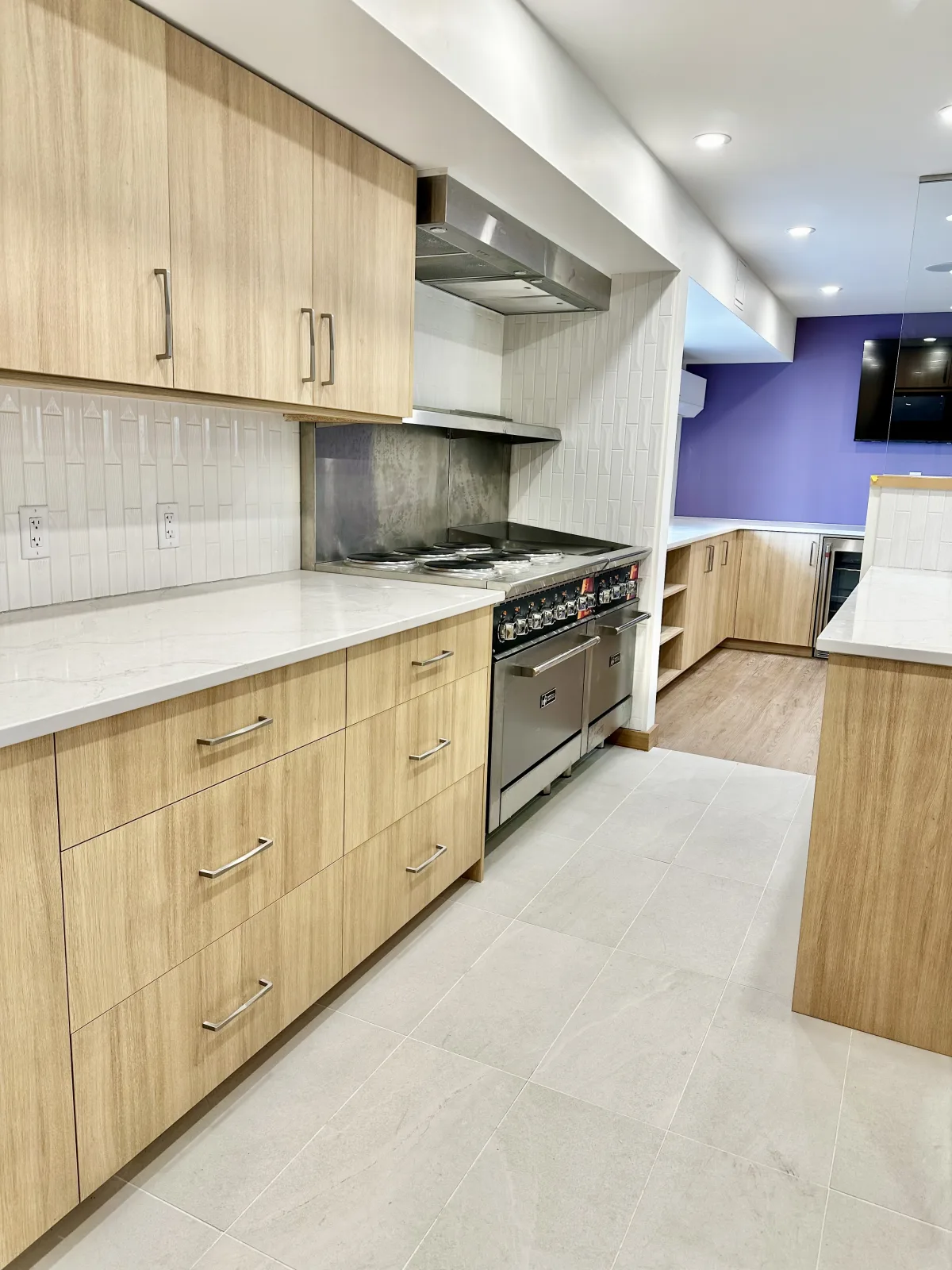 Light oak kitchen with a professional range and full height tile backsplash
