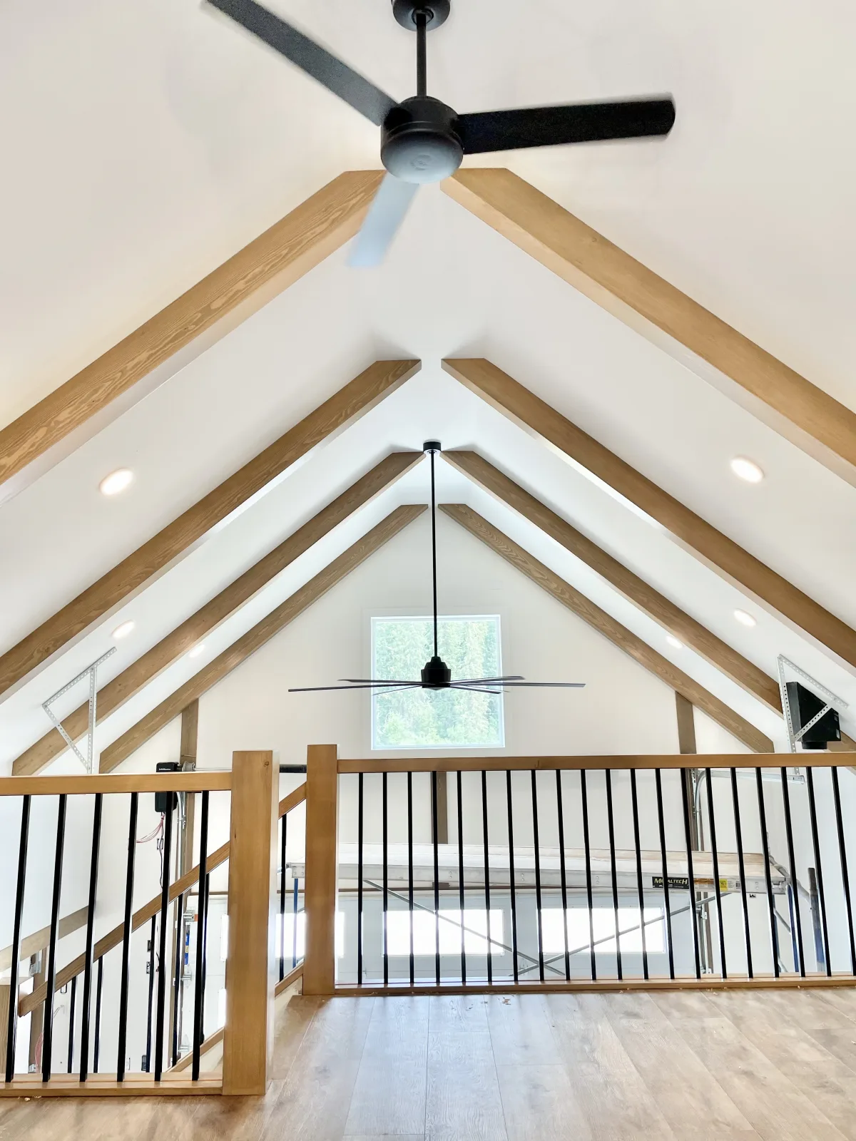 Vaulted ceiling with exposed beams above a timber and steel loft railing