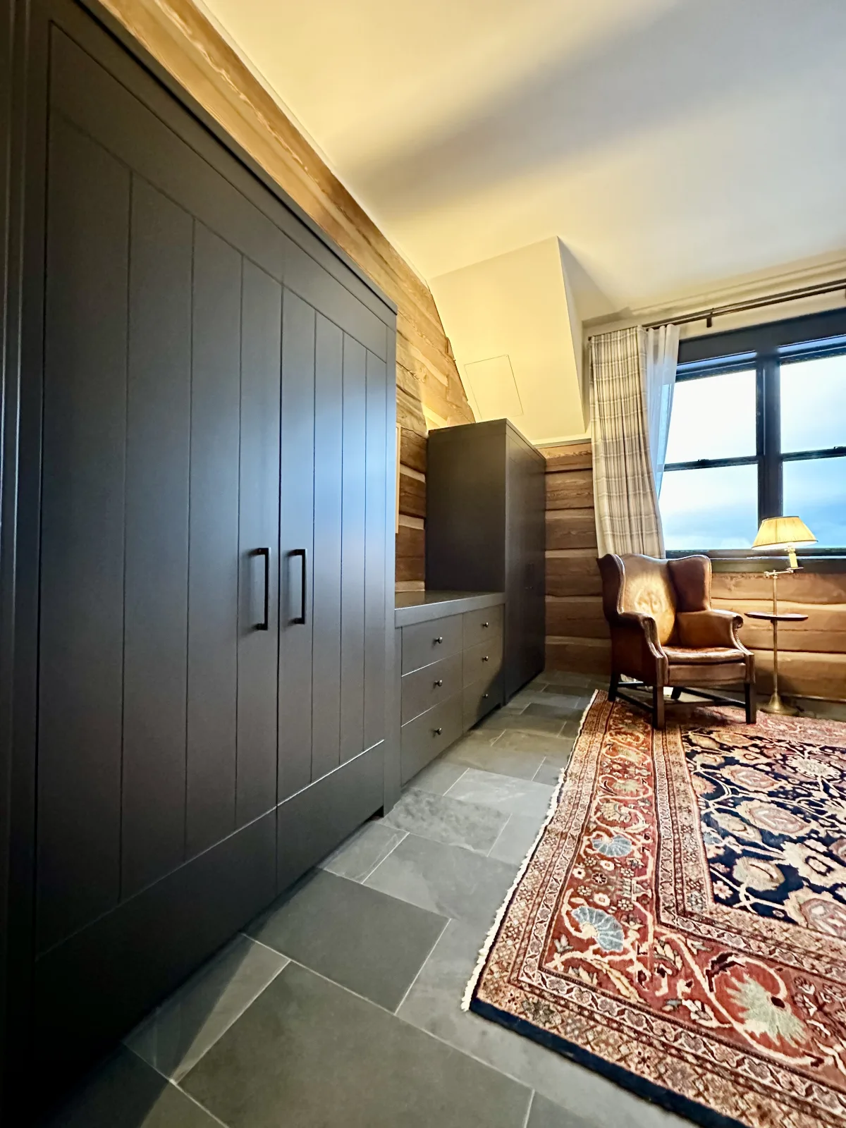 Charcoal wardrobe run in a log walled bedroom over a flagstone floor