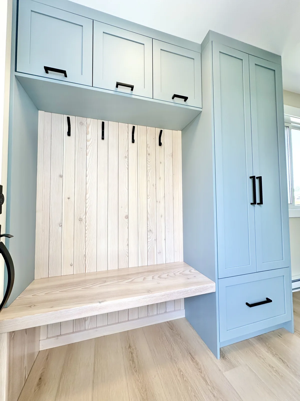 Blue mudroom bench and lockers with a whitewashed plank back