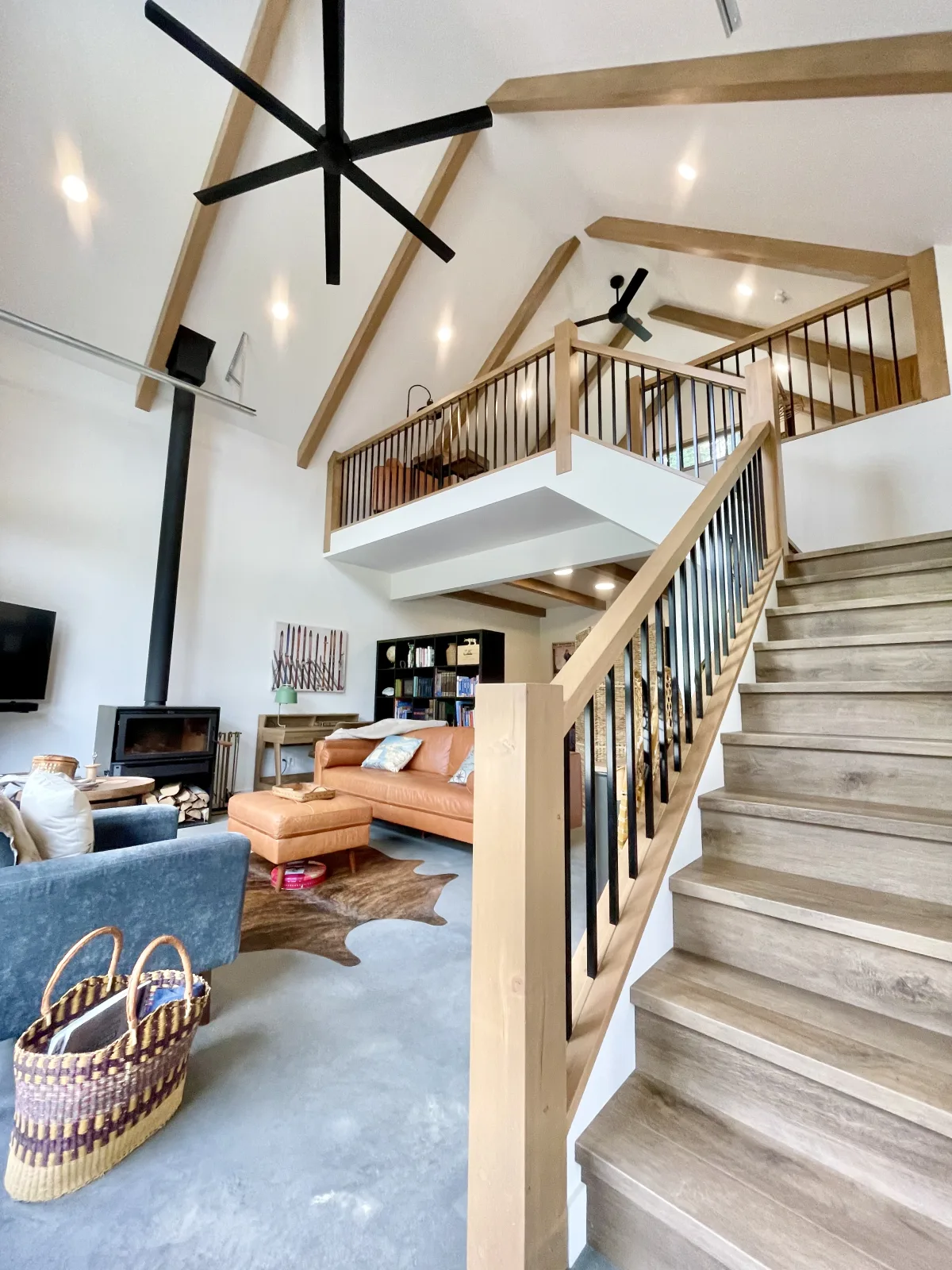 Open great room with a timber stair, steel spindle railing and a loft above