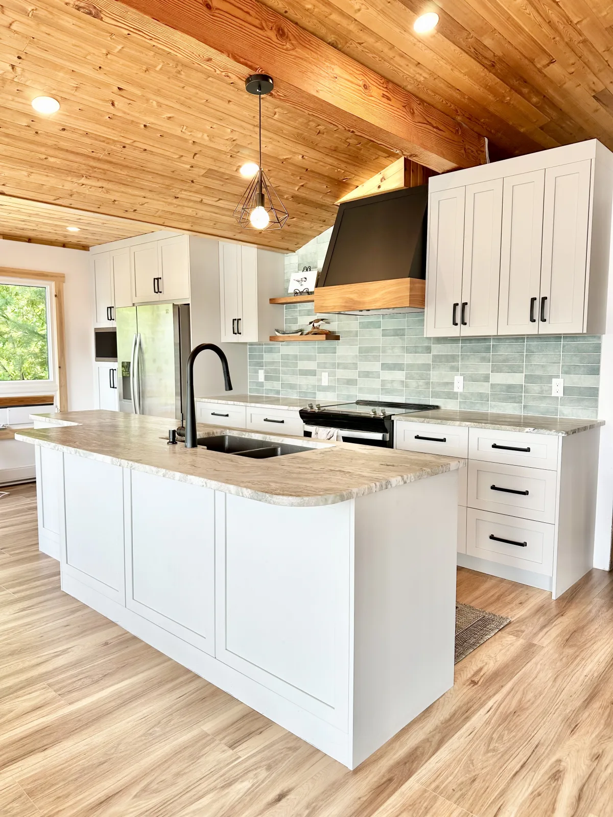 White shaker kitchen with a stone island under a pine plank ceiling